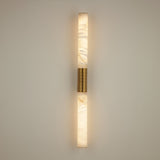 Niori Eryon LED large wall light with two natural alabaster cylinders joined by a brushed brass and ribbed bronze centre mount, illuminated on a pale wall.