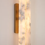 Close-up of the Selvara Small LED double wall light, showing two offset alabaster panels with grey veining lit from within, set in a brushed brass frame and backplate against a plain wall.