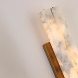 Close-up of the Selvara LED Large Alabaster Double Wall Light, showing two vertical alabaster columns glowing warm white on a brushed brass backplate against a plain wall.