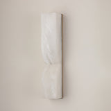 Vera LED Small Silhouette Alabaster Wall Light in soft white, an hourglass-shaped column with brushed brass edge trim, mounted on a plain light wall.