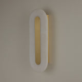 Niori Averra 800mm alabaster wall light with elongated rounded white panel and recessed brass linear detail, mounted on a neutral wall.