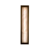 Niori Valora LED vertical wall light illuminated, showing a tall Spanish alabaster panel with mineral veining set in a brushed brass rectangular frame.