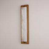 Niori Valora vertical wall light with tall natural alabaster panel in a slim brushed brass rectangular frame, mounted on a pale neutral wall.