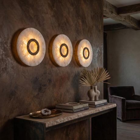 Three round Ovaline LED alabaster wall lights, 35cm, with brushed brass hammered ring detail, glowing warmly on a wall above a console table in a hallway.