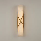 Valora LED Alabaster Wall Light in brushed brass, a vertical alabaster column wrapped by crossing brass bands, glowing warm white on a plain light background.