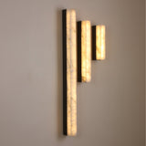 Niori Cornova 450mm slim linear alabaster wall lights in matte black, shown in three staggered heights glowing warm white against a neutral wall.