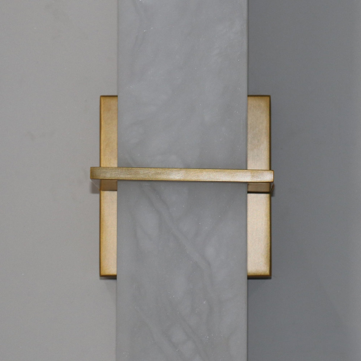 Aurevon LED wall light with vertical alabaster panel and brushed brass backplate, horizontal brass bar detail, close-up view on grey background.