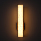 Aurevon LED vertical wall light with rectangular alabaster panel, brushed brass backplate and arm, glowing warm-white against a dark background.