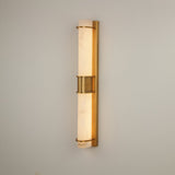 Niori Averna LED framed alabaster wall light with two stacked cylinders in a brushed brass frame and central collar, mounted on a light wall.