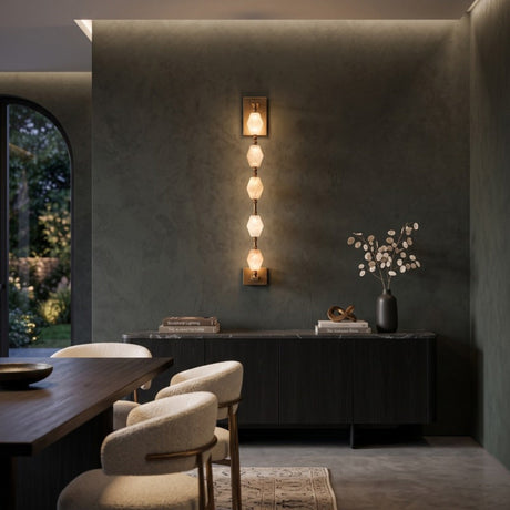 Brisalda 5 Light Faceted Alabaster Wall Light in brushed brass, mounted vertically on a dark wall above a sideboard in a dining room setting.