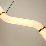 Close-up of the Zareon Small LED chandelier's stepped alabaster tube glowing warm white, joined by brushed brass collars and black cable drop, against a plain grey background.