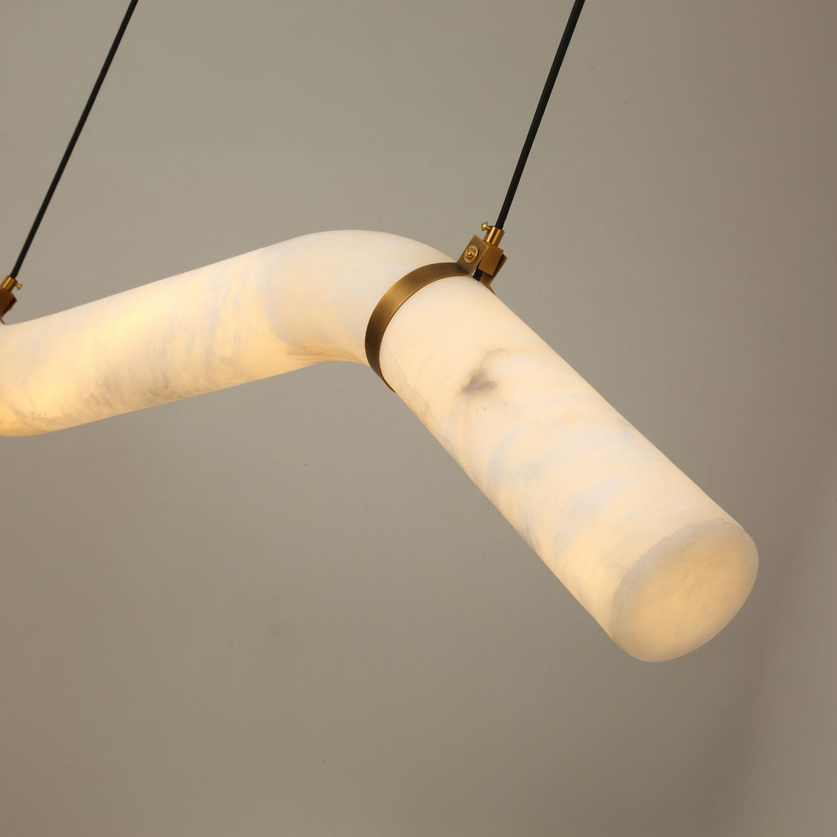 Zareon Small LED chandelier featuring a stepped alabaster tube joined by a brushed brass collar, suspended on black cables against a plain light grey background.