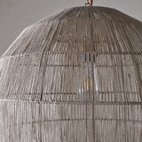 Close-up of the Nilaveli Woven Jute Sphere Pendant Light in natural tones, showing dense vertical thread winding over a visible frame with a glowing bulb inside.