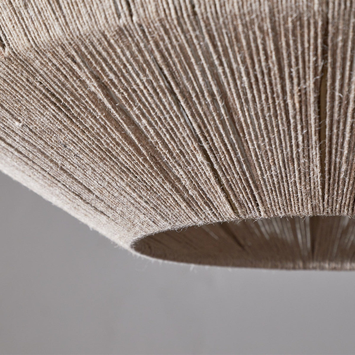 Close-up of the Nilaveli Woven Jute Sphere Pendant Light in natural, showing dense vertical jute thread winding over a hidden metal frame with an open base opening.