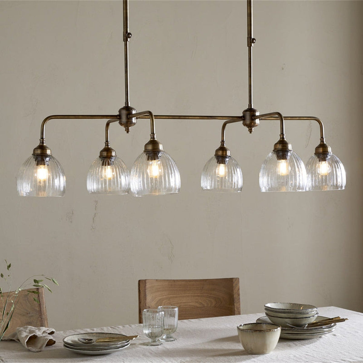 Kakira Ribbed Glass 6 Light Chandelier - Clear & Antique Brass in a dining room