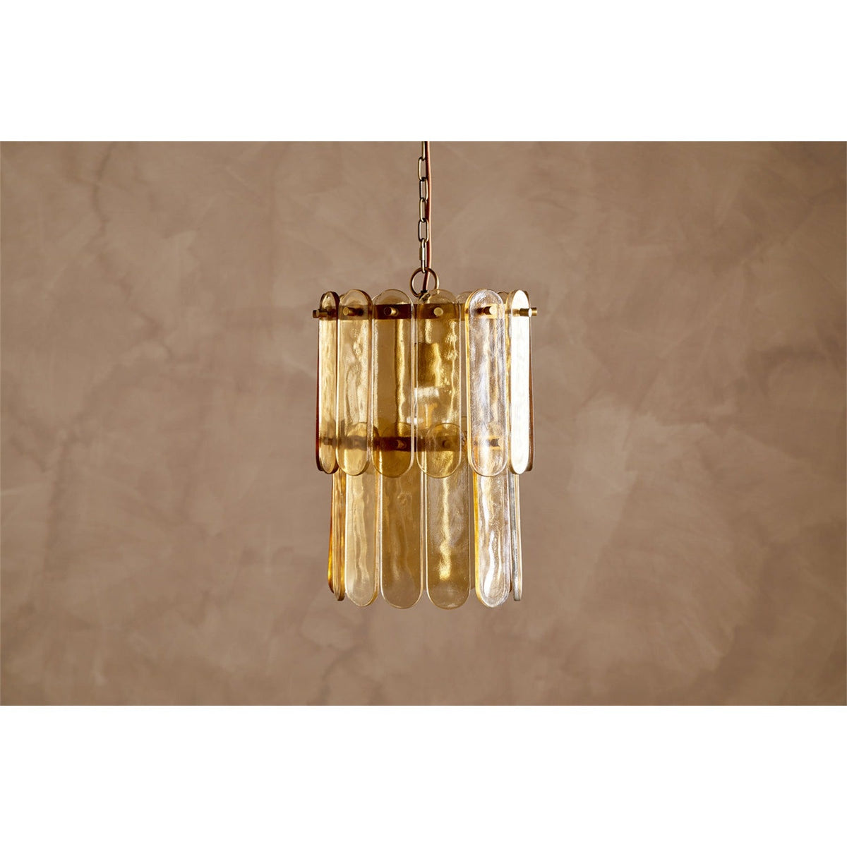 Itan Tiered Recycled Glass Pendant Light in Amber, featuring flat rounded glass paddles pinned to two brass rings in overlapping tiers, suspended on a chain against a plain neutral background.
