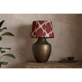 Haadu Large Jute Kilim Lampshade in rust and natural wool, shown atop a hammered bronze-finish lamp base on a wooden sideboard.