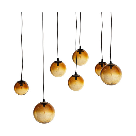 Jerami 7 Light Recycled Glass Linear Chandelier in Caramel, seven round caramel glass globes with black caps hung at staggered heights on black flexes, shown on a white background.