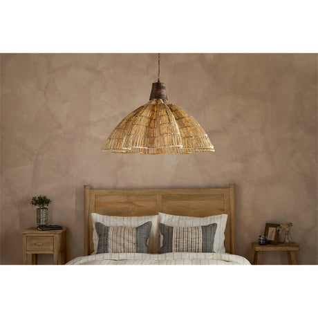 Tudai Large Woven Jute Pendant Light in natural, a wide dome shade with lobed rim and mango wood collar, shown above a bed in a warm-toned bedroom.