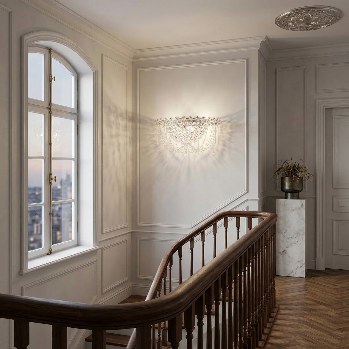 Elegant hallway with a wooden staircase, white panelled walls, large city-view window, and the Amara 2 Light K9 Crystal Flush Ceiling Light in chrome casting luminous patterns over a marble pedestal topped with a decorative vase of dried plants.
