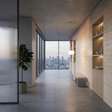 A modern, minimalist hallway with large windows overlooking a city skyline, light wood shelving with decor, a small potted plant, a Yoyo Pendant Light - Copper overhead, and a concrete bench.
