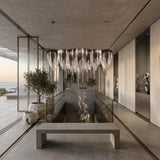 Niori Symphonia 10 Light Metal Chain Veil Chandelier in nickel suspended above a concrete bench and reflecting pool in a minimalist coastal interior.
