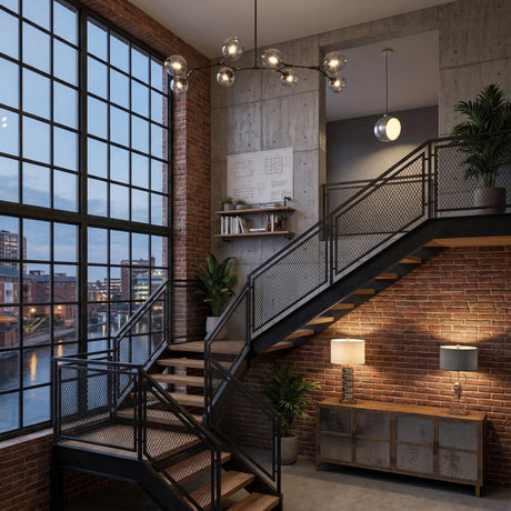 Niori Tree 8 Light Suspension in black with branching arms and glass globes, hanging in an industrial loft with brick walls, tall windows, and metal stairs.