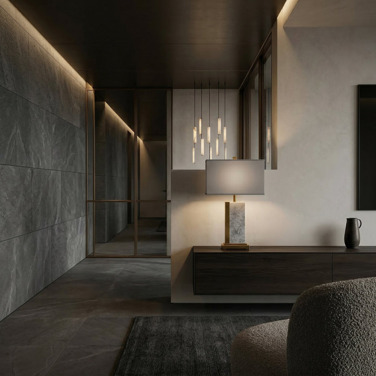 A modern, minimalist living space with dark stone walls, a sleek floating sideboard, Vellum 1 Light Structured Form Marble Table Lamp in brass & grey, pendant lights, large floor tiles, and warm recessed lighting for a cozy feel.
