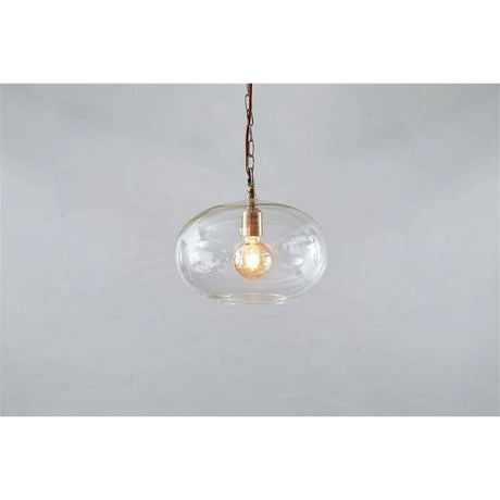 Otoro Small Round Recycled Glass Pendant Light in clear, a flattened spherical shade with brass collar and visible E27 bulb, hung on a brass chain against a plain light background.