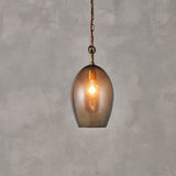 Otoro Small Oval Recycled Glass Pendant Light in Smoke, an egg-shaped glass shade with brass collar, ceiling rose, and chain, rust fabric flex, lit bulb visible, on a plain grey background.