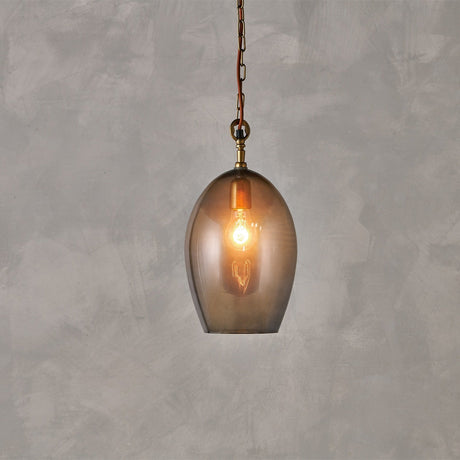 Otoro Small Oval Recycled Glass Pendant Light in Smoke, an egg-shaped glass shade with brass collar, ceiling rose, and chain, rust fabric flex, lit bulb visible, on a plain grey background.