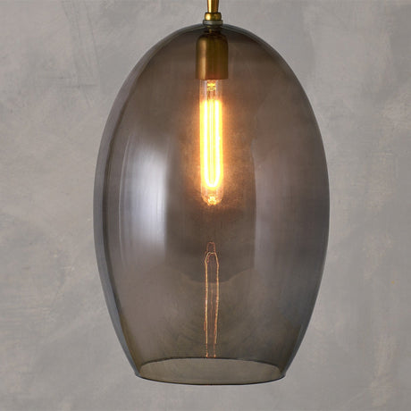Otoro Large Oval Recycled Glass Pendant Light in smoke, an egg-shaped shade with brass collar and chain, exposed bulb, shown on a plain grey background.