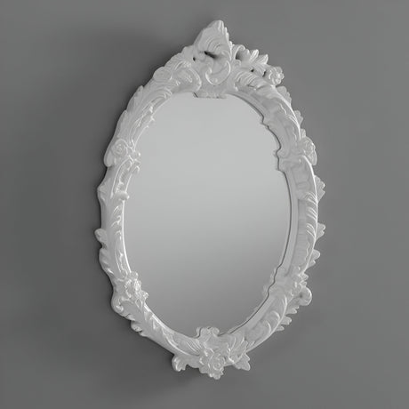 The Illuna Oval Wall Mirror White - 64x46cm, featuring an ornate design with intricate floral and leaf patterns on its white frame, stands out as a striking piece of home decor against a plain gray background.