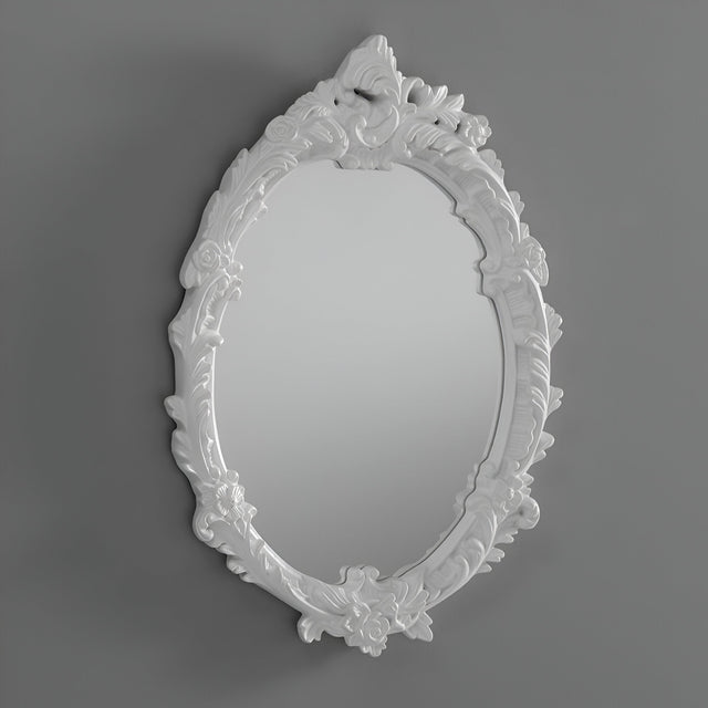 The Illuna Oval Wall Mirror White - 64x46cm, featuring an ornate design with intricate floral and leaf patterns on its white frame, stands out as a striking piece of home decor against a plain gray background.