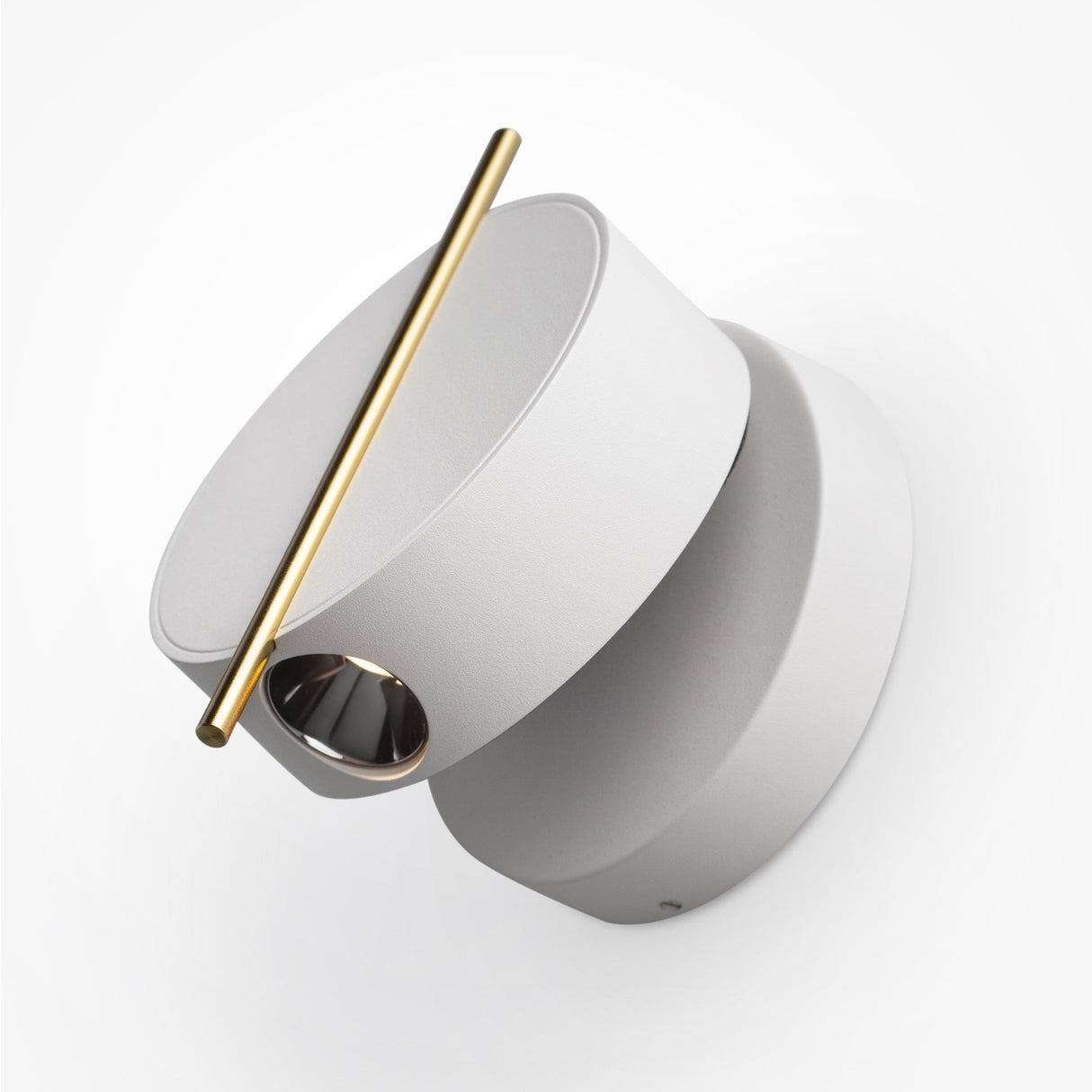 The Nuance LED Movable Head Wall Light in white with gold detail features minimalist design, comprising two overlapping circular sections. One section is tilted and has a brass rod diagonally across the top, while a small opening unveils a reflective interior for enhanced energy efficiency.