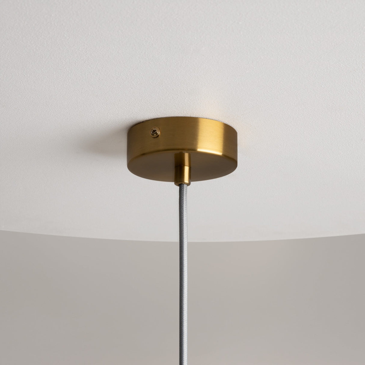 A brass Mood Globe Pendant Light adorns the white ceiling, featuring a round canopy and a gray cord suspending a clear glass shade.