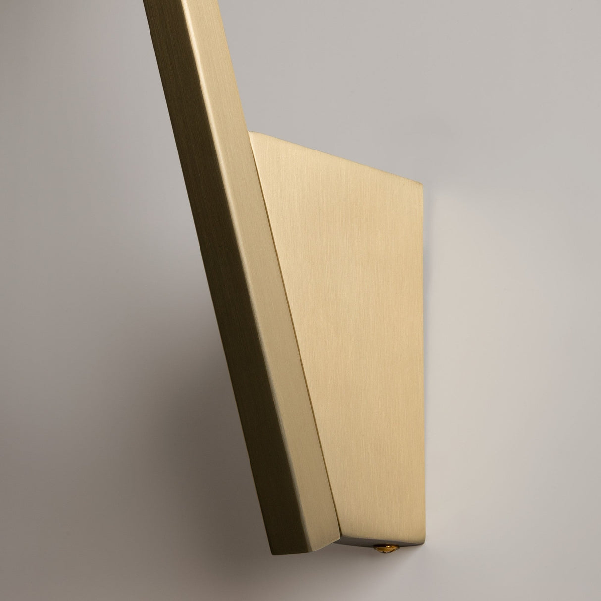 A sleek, contemporary Kazimir Wall Light in gold with white opal glass, mounted on a light-colored surface. Its minimalist design features smooth edges and a rectangular shape, embodying avant-garde style while showcasing its modern elegance from the side view.