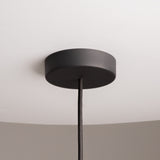 The Cane Pendant Light 30cm in black wicker, featuring a white glass diffuser and adjustable wire, hangs elegantly against a light gray background, adding a modern natural design to any room.