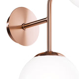 A close-up of the Erich 2 Light Wall Light in brass showcases a minimalist aesthetic with a round base and arm supporting a white frosted glass globe, its ambient design perfectly complementing elegant styles.