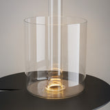 The AI Collaboration Rechargeable LED Table Lamp with Glass Vase - Gold features a transparent cylindrical design, emitting a warm glow that reflects ambient light, creating a sleek and minimalist aesthetic against a neutral background.