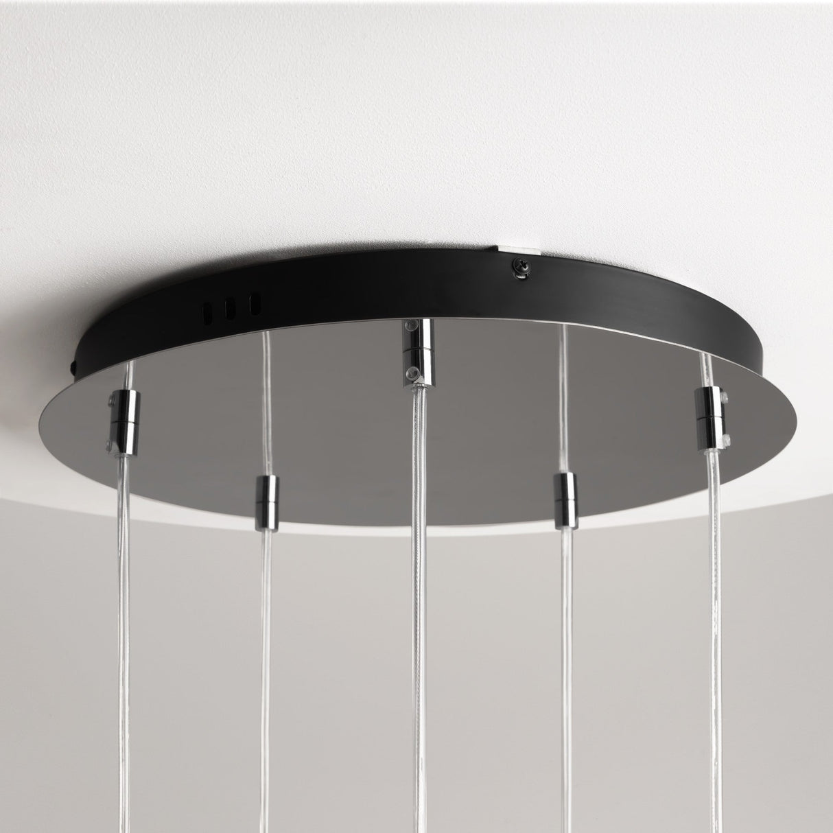 The Drop LED Cluster Pendant Light 80W 3000K - Chrome features a chrome black circular base with transparent cords hanging from it, showcasing an energy-efficient, minimalist, and contemporary design against a light-colored ceiling.