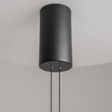 A close-up of the Ambience LED Round Flat Small Pendant Light - Black, featuring two thin wires that enhance its modern elegance against a plain, light gray background.