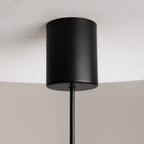 The Sixth Sense LED Pendant Light, featuring a modern black cylindrical design with a matte finish and white glass, is mounted on the ceiling. The sleek fixture enhances its minimalist appeal as it hangs elegantly.