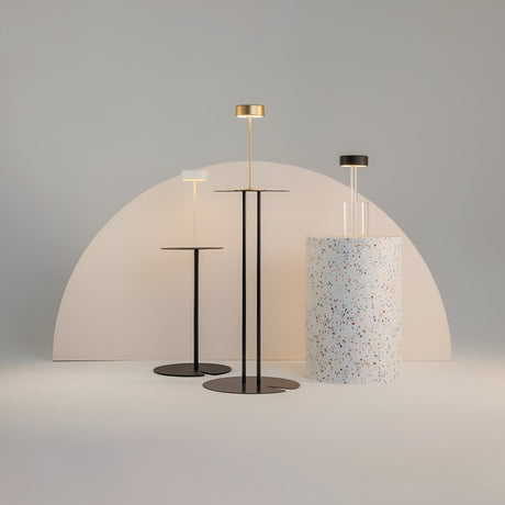 Three modern floor lamps stand against a minimalistic backdrop: two are gold finish LED lamps with black bases and shades, while the third is an AI Collaboration lamp with a white shade. A terrazzo-patterned cylinder adds texture to this simple yet elegant scene.