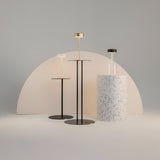 Against a minimalist backdrop, three AI Collaboration Rechargeable LED Table Lamps in white shine as an eco-friendly lighting solution with sleek black bases, their circular shades perfectly complementing the terrazzo-patterned cylindrical pedestal.