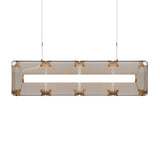 Niori Qbic LED Large Linear Suspension Light in clear smoked glass with exposed brass corner brackets and a central LED tube, hung from twin steel cables.