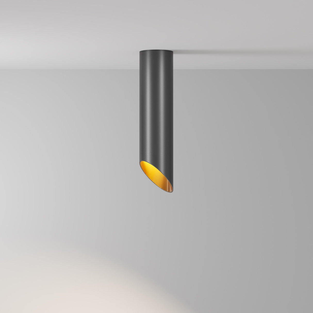The Lipari Long Surface Mounted Downlight 25cm - Black & Gold features a sleek black cylindrical design with a gold inner lining, casting a soft circular glow on a plain white wall as it angles downward.
