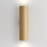 The Artisan Wall Light - Matte Gold is a textured cylindrical lamp with a matte gold finish, installed vertically on a white wall. It emits soft white light from both ends, adding contemporary design and subtle illumination.