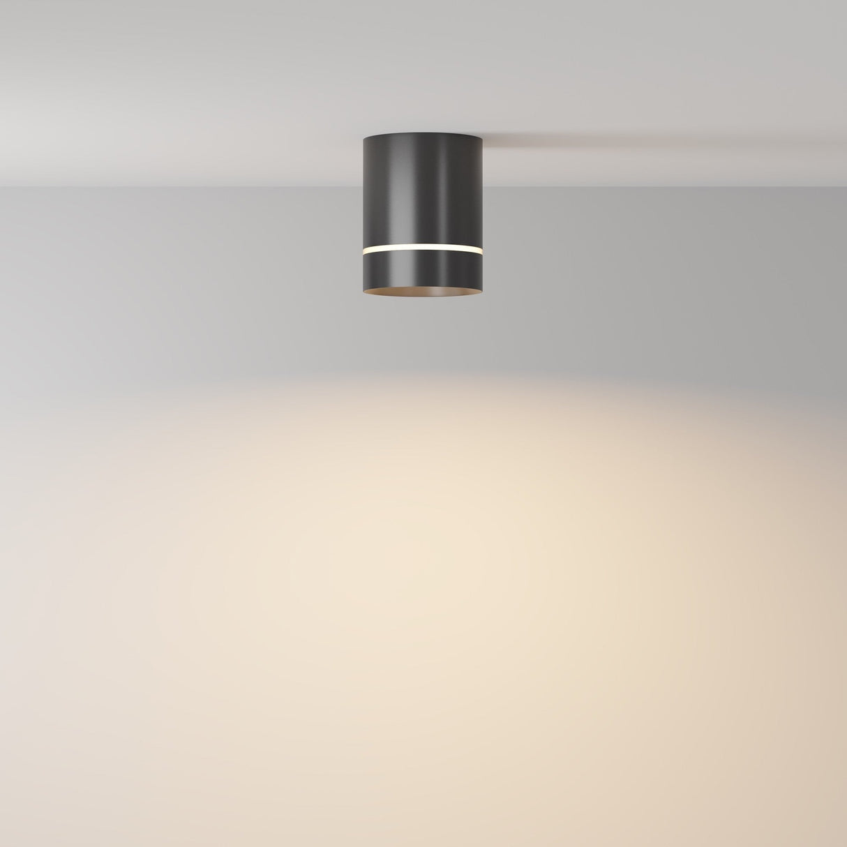 The Orlo LED Round Surface Downlight 9W 3000K in black is installed on a white ceiling, casting an energy-efficient, warm glow on the wall and ceiling below.