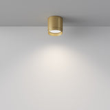 The Polar Round Surface Downlight in Matte Gold casts a soft, circular glow on a white wall, with its minimalist design contrasting against the plain backdrop to create a modern and elegant ambiance.